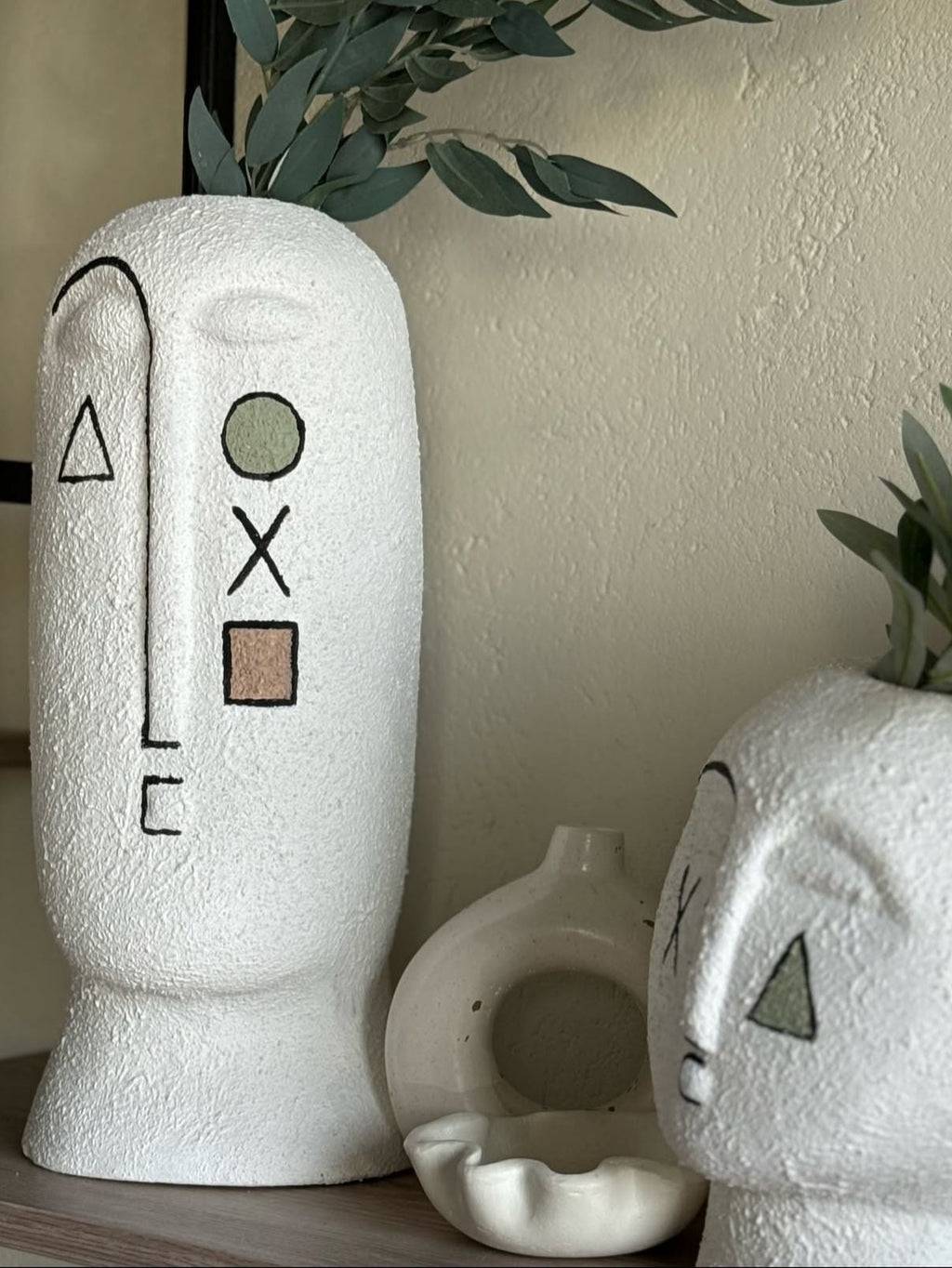 White textured vases with minimalist face designs on a neutral background