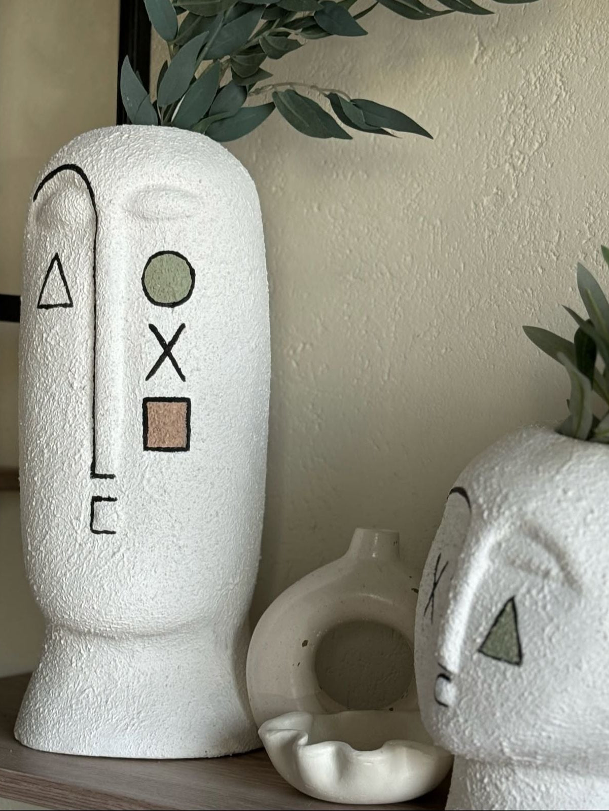 White textured vases with minimalist face designs on a neutral background